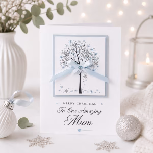 White Christmas card featuring a delicate winter tree surrounded by blue and silver snowflakes, finished with a pale blue satin bow.