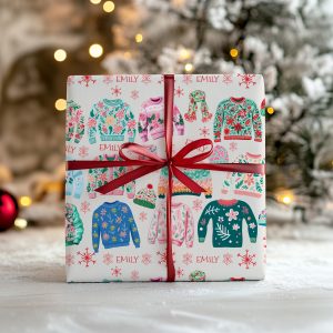Personalised Christmas Jumper Wrapping Paper, wrapped with a red ribbon at the base of a Christmas tree