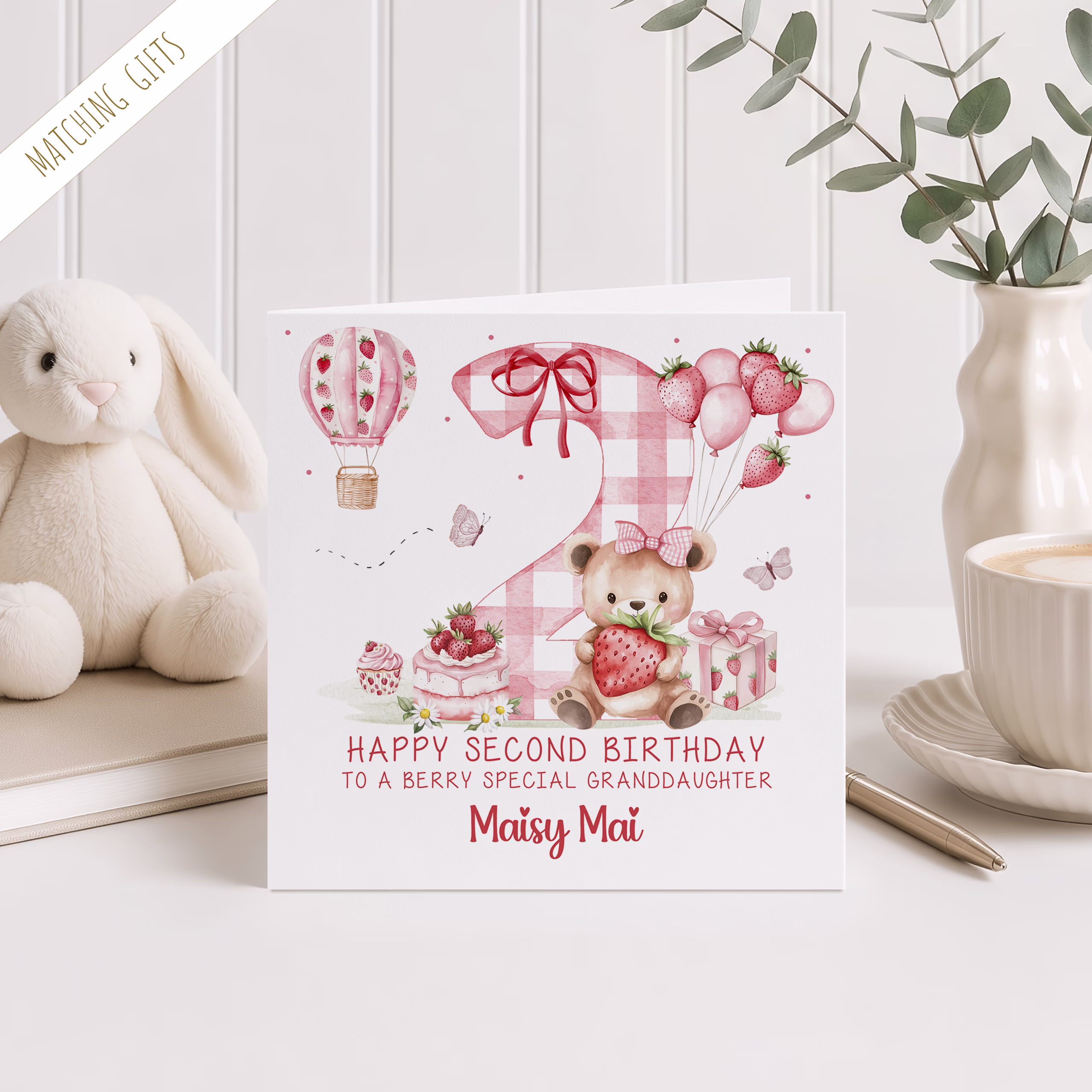 Girls Second Birthday Card in a square design, with a strawberry design, with a giant pink gingham number two in the backround and a strawberry hot air balloon