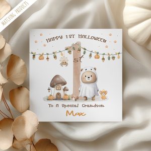 personalised baby's 1st halloween card featuring a cute teddy bear wearing a ghost sheet costume, standing next to a large number one with a pumpkin garland.