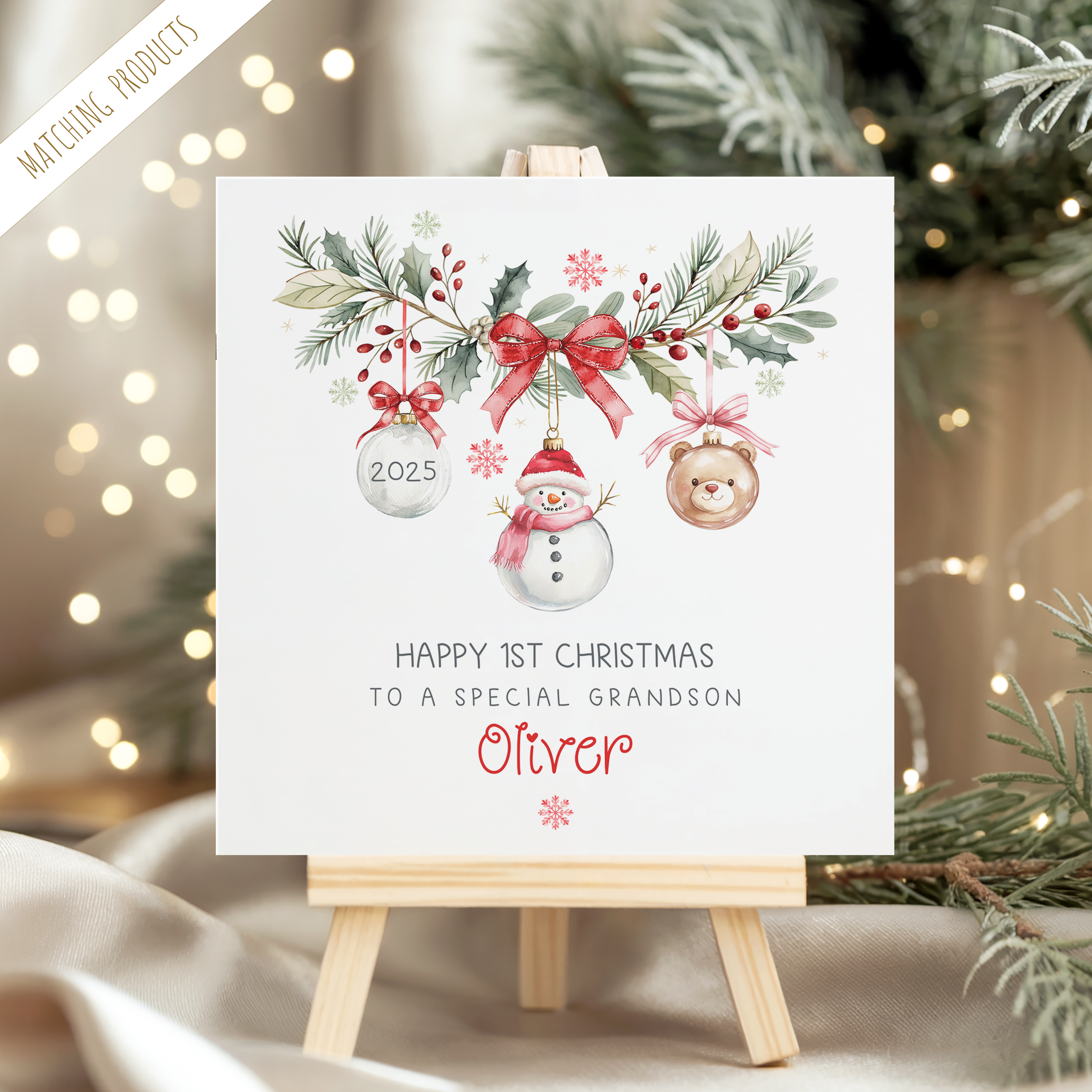 baby's 1st personalised christmas card featuring a festive wreath with a snowman, teddy and clear christmas bauble hanging from it. The baby's name appears underneath.
