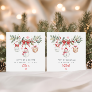 baby's 1st personalised christmas card featuring a festive wreath with a snowman, teddy and clear christmas bauble hanging from it. The baby's name appears underneath.