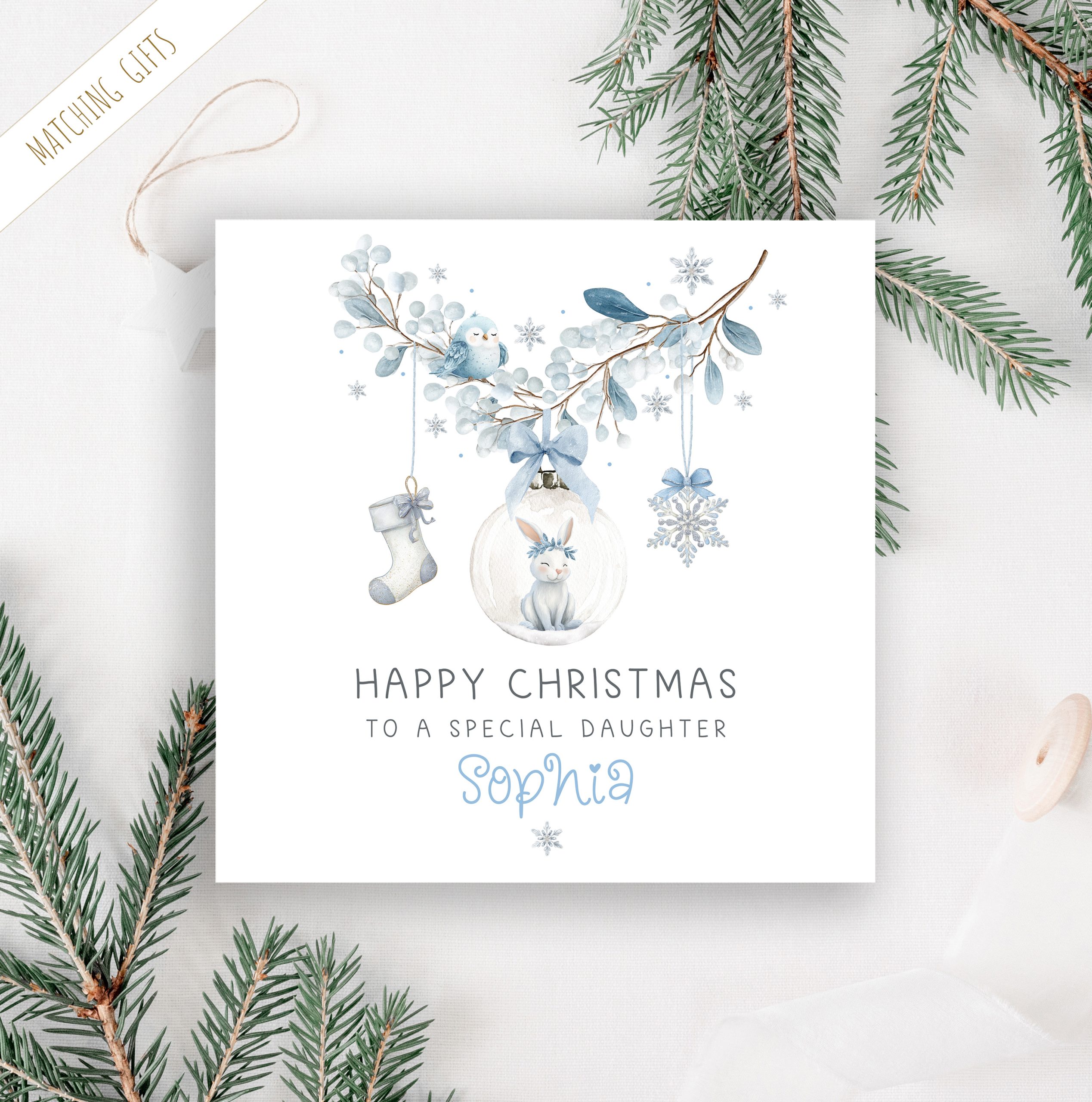 Girls personalised bunny rabbit christmas card. Featuring a blue floral wreath with christmas baubles hanging from it, a star, a christmas stocking and a bauble with a cute bunny rabbit. The card is personalised at the bottom with a name in blue ornate christmassy font.