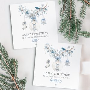Girls personalised bunny rabbit christmas card. Featuring a blue floral wreath with christmas baubles hanging from it, a star, a christmas stocking and a bauble with a cute bunny rabbit. The card is personalised at the bottom with a name in blue ornate christmassy font.