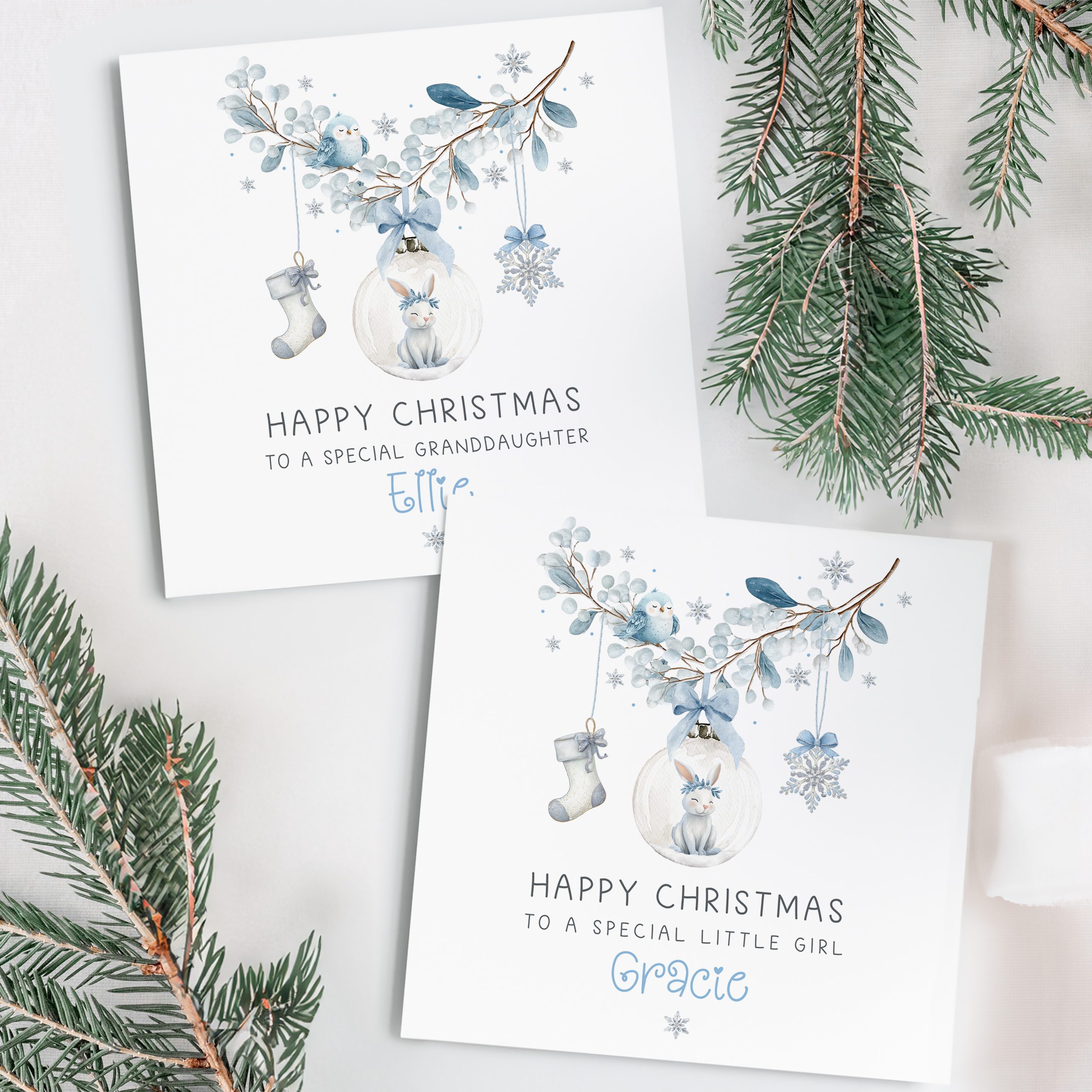 Girls personalised bunny rabbit christmas card. Featuring a blue floral wreath with christmas baubles hanging from it, a star, a christmas stocking and a bauble with a cute bunny rabbit. The card is personalised at the bottom with a name in blue ornate christmassy font.