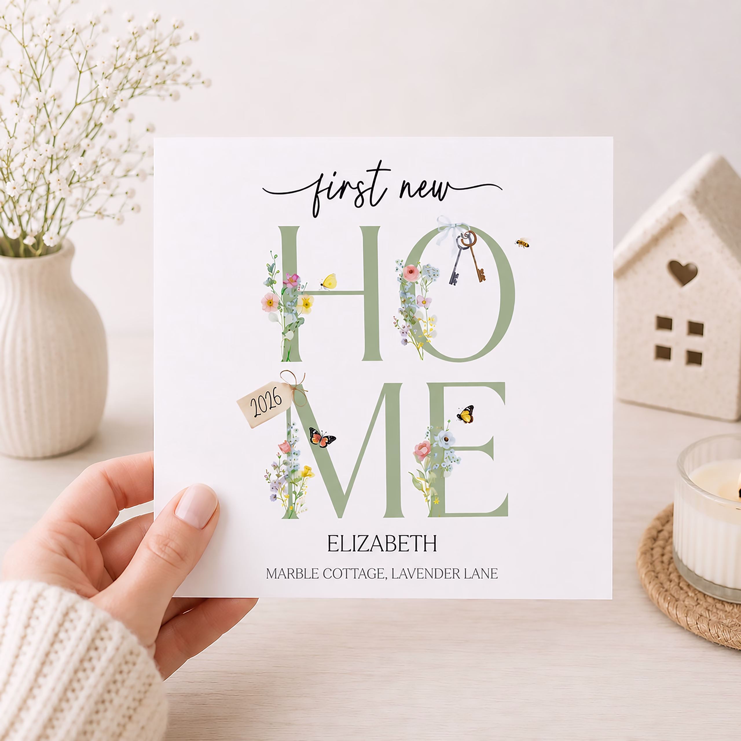 Square new home card featuring floral HOME lettering, butterflies, keys and personalised names and address.