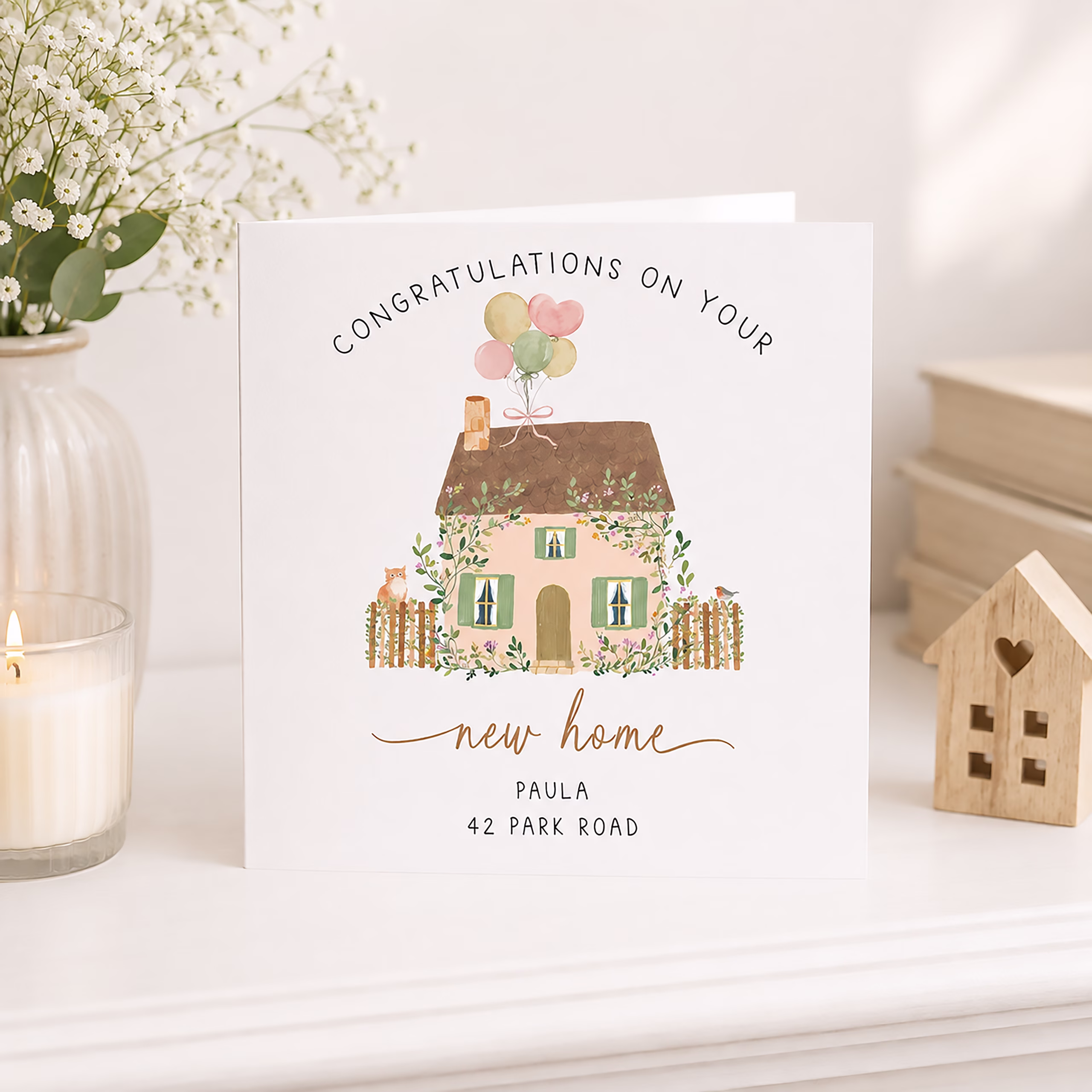Personalised new home card with a watercolour cottage, balloons, flowers and the recipient's name and address.