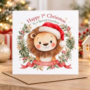 Cute baby's first Christmas card with an illustrated lion, festive Santa hat, Christmas berries and personalised ribbon.